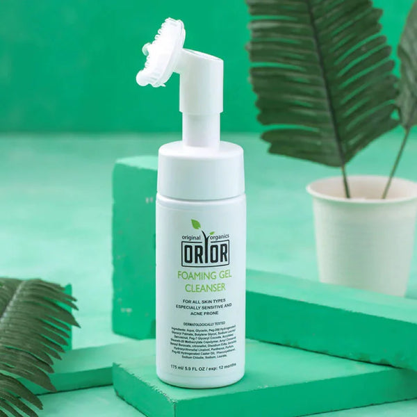 White foaming gel face cleanser for oily skin bottle displayed against a green background with a cup featuring plant leaves